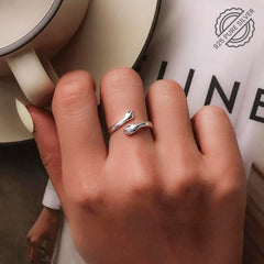 A woman clutches a cup of coffee, showcasing a Tizzarat Sliver Hug Ring.	