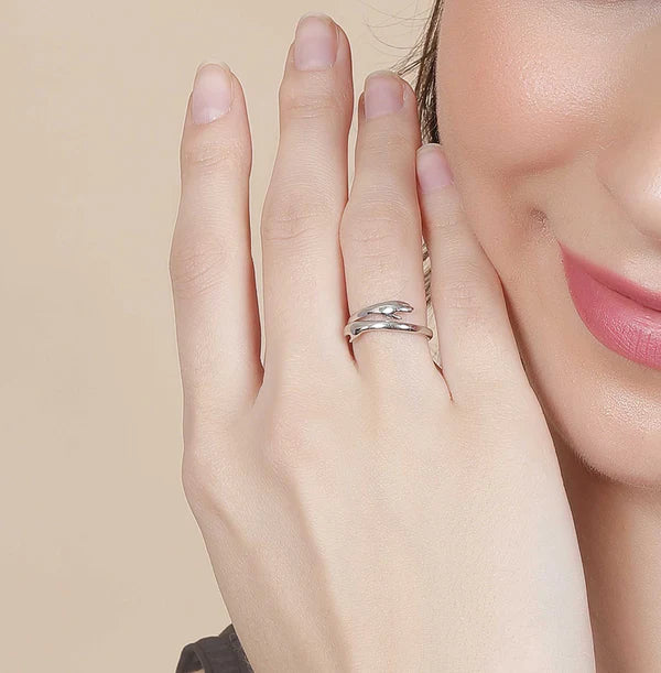 A woman clutches a cup of coffee, showcasing a Tizzarat Sliver Hug Ring.	